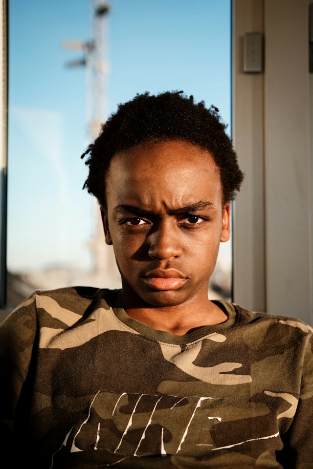 An unhappy teenager wearing a Nike shirt with a camouflage pattern.