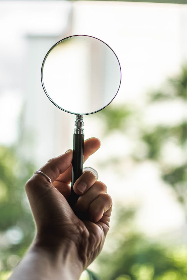 A person holds a magnifying glass with a black handle.