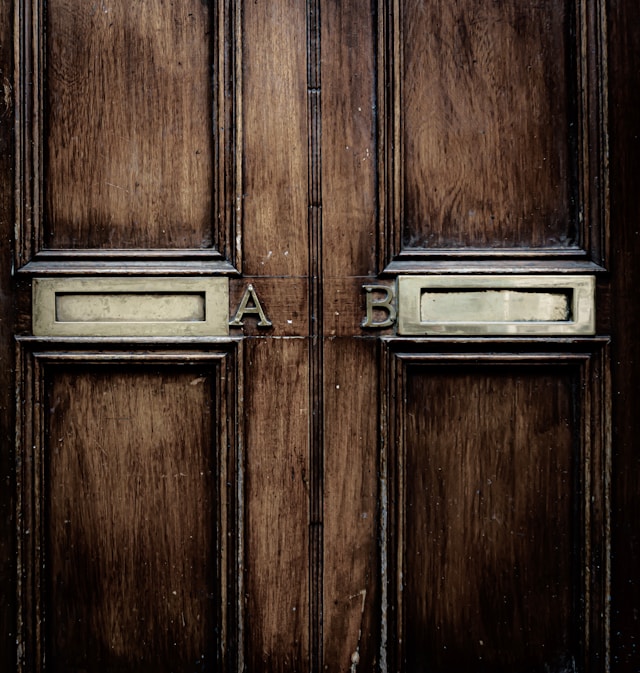 A brown wooden door with two metallic mailboxes.
