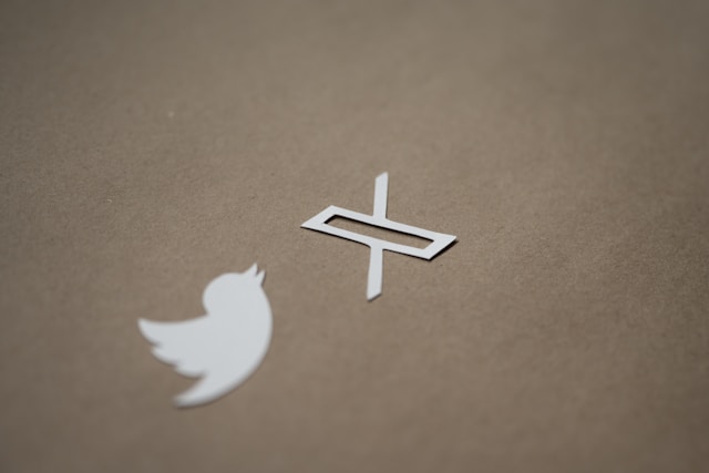 A white cutout of Twitter’s old and new logo on a brown background.
