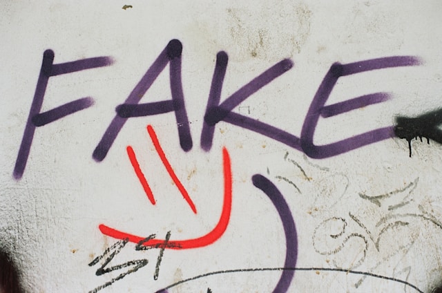 The word “fake” graffitied on a wall.
