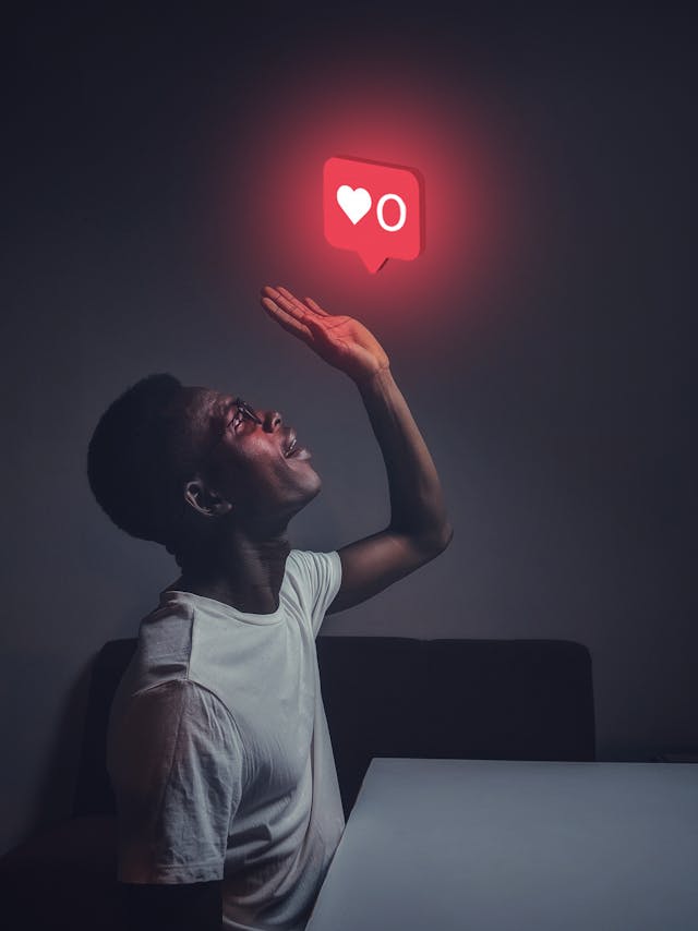 A man with a white shirt looks at a red chat bubble with a heart and a zero.