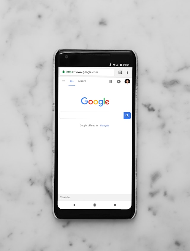 La homepage di Google Search sul browser mobile di uno smartphone nero.
