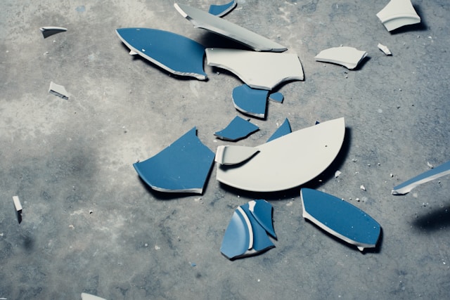 A close-up of a broken blue and white plate on a gray background.