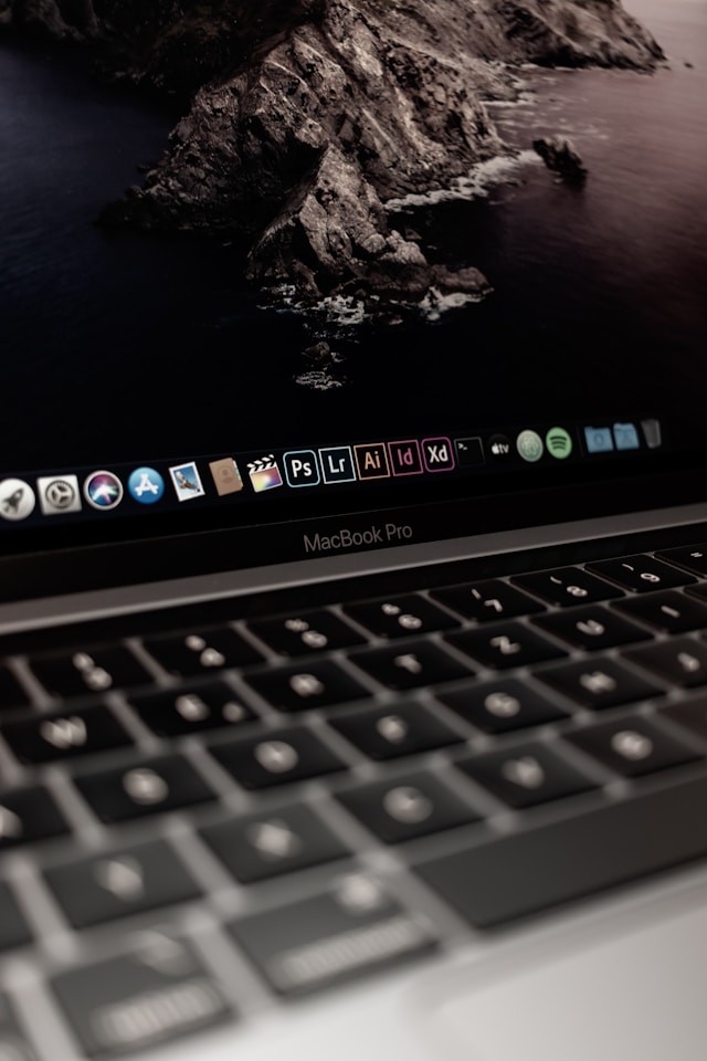 Gros plan sur le dock de macOS avec plusieurs icônes d'applications sur un MacBook Pro gris.

