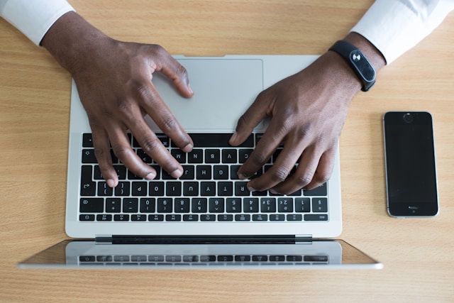 A person’s hands type on a laptop.
