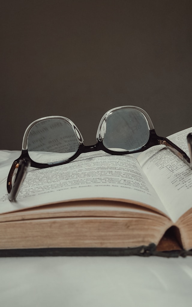 Une paire de lunettes à monture noire sur un livre ouvert.