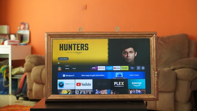 Amazon Fire OS pada TV dengan bingkai kayu berwarna coklat muda di atas meja.