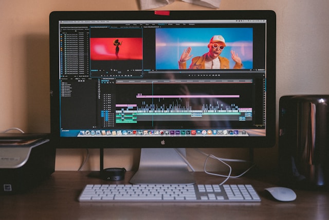 Ein schwarzer Apple Mac Pro mit einem Apple-Monitor, einer Tastatur und einer Magic Mouse auf einem braunen Holztisch.
