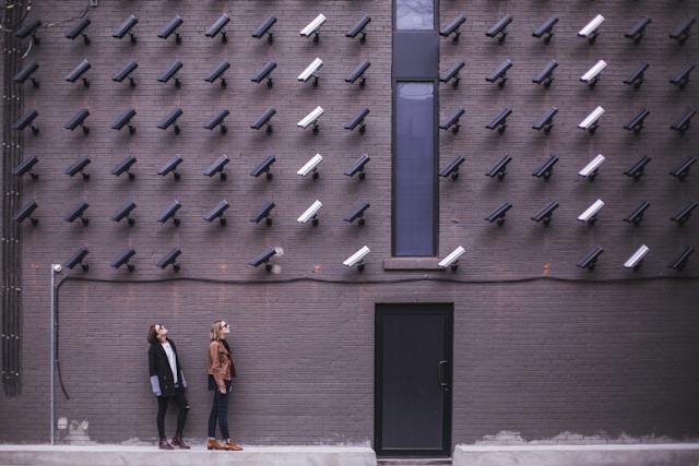 Deux femmes regardent plusieurs caméras de sécurité sur un mur.