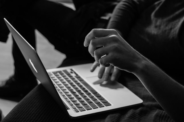 Eine Person verwendet das Trackpad eines grauen Macbooks.
