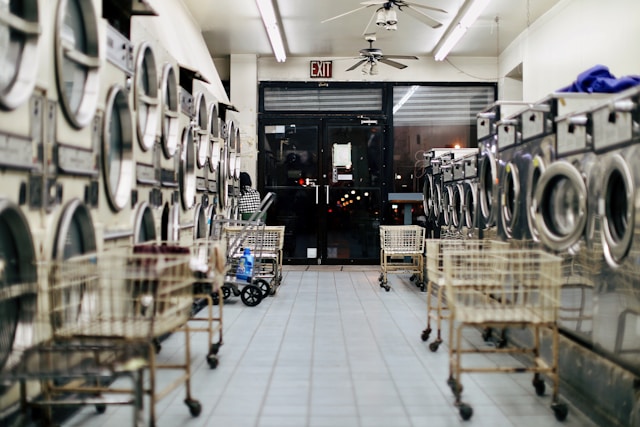 Ein Waschsalon mit mehreren Waschmaschinen und Wäschewagen.