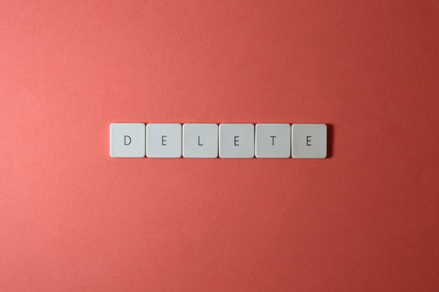 كلمة "حذف" على بلاط أبيض يشبه لوحة المفاتيح على خلفية حمراء ترابية.