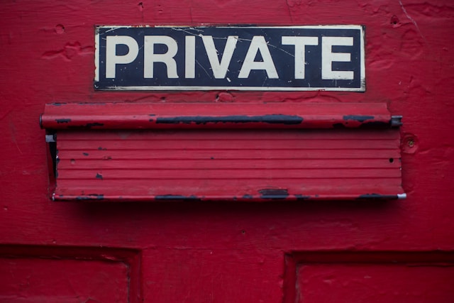 赤い壁に白いペンキで「プライベート」と書かれた濃紺の看板。