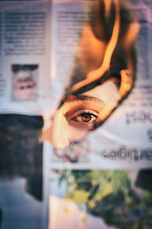 A person looks through a burning piece of paper.