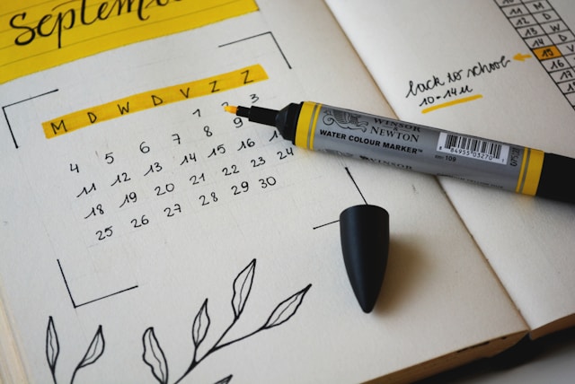 Een close-up van een pagina met een handgetekende kalender en een gele aquarelstift.