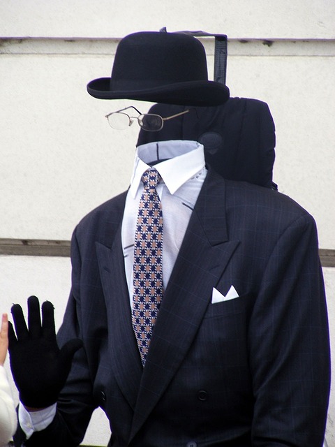 A person with a black suit and hat performs an illusion trick to make it look like he’s invisible.