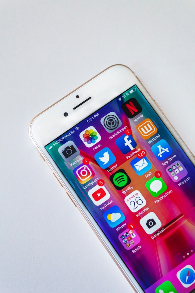 صورة مقربة لجهاز iPhone أبيض اللون مع تطبيقات متعددة على شاشته الرئيسية.