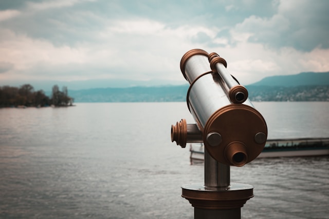 Un télescope argenté et cuivré au bord d'un lac.