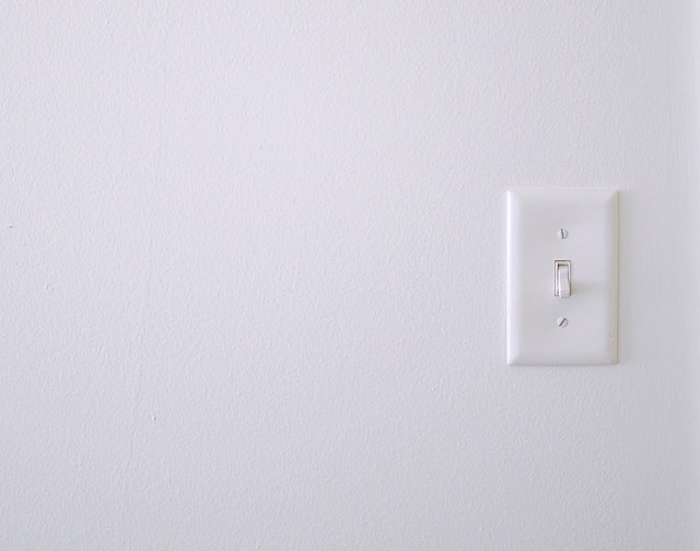 A white wall with a white light switch.