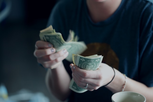 A close-up of a person with a blue shirt that counts money.