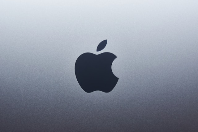 A close-up of the black Apple logo on a light gray background.