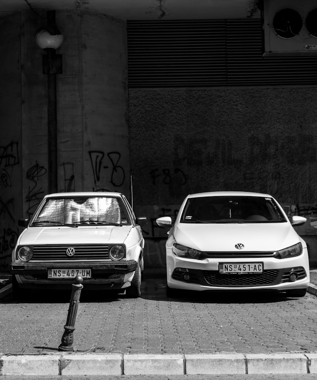 Um modelo mais antigo do Volkswagen Golf está ao lado de uma versão mais recente do mesmo automóvel.