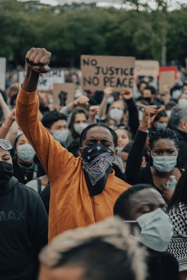 Eine Gruppe von Demonstranten mit Masken hält ihre Hände mit geballten Fäusten.