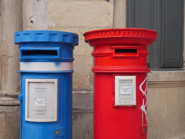 Une boîte aux lettres bleue à côté d'une boîte aux lettres rouge.