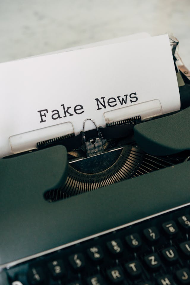 Une machine à écrire verte avec le texte "fake news" sur une feuille de papier.