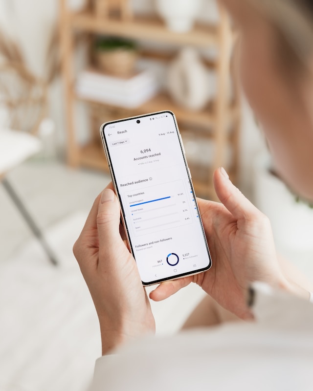 A person looks at their analytics dashboard on a white Samsung smartphone.