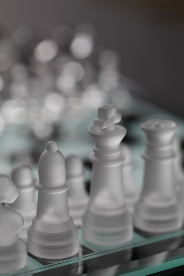 A close-up of translucent chess pieces on a glass board.