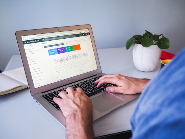 A person with a blue shirt looks at the Google Search Console dashboard on a gray MacBook Air.