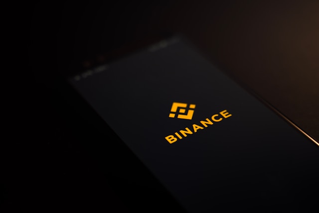 Das Binance-Logo auf dem Bildschirm eines schwarzen Smartphones.