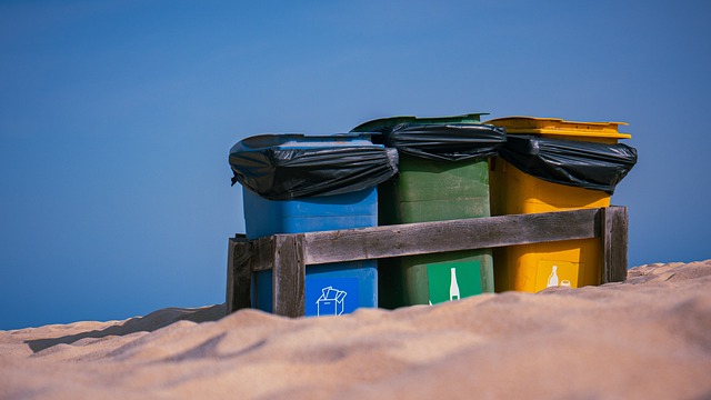 Primer plano de tres cubos de basura en una playa.