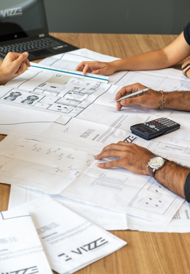 A group of people look at various diagrams on large sheets of paper.