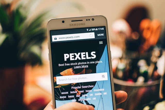 Eine Person ruft mit ihrem weißen Samsung-Smartphone die Pexels-Website auf.