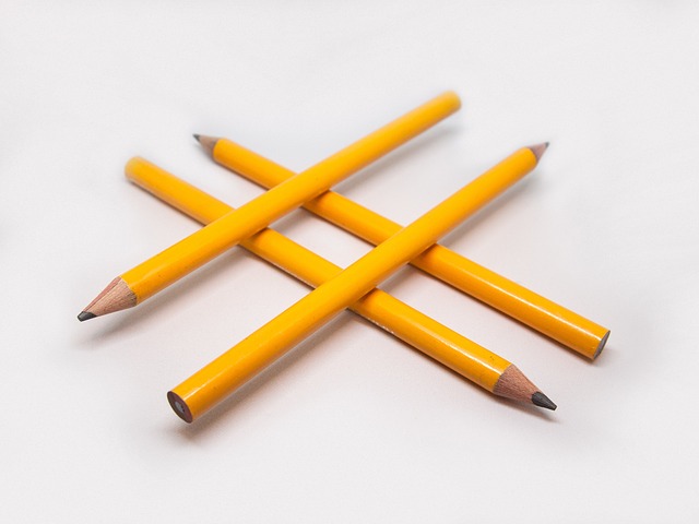 Quatre crayons jaunes utilisés pour illustrer le symbole du hashtag sur une surface blanche.