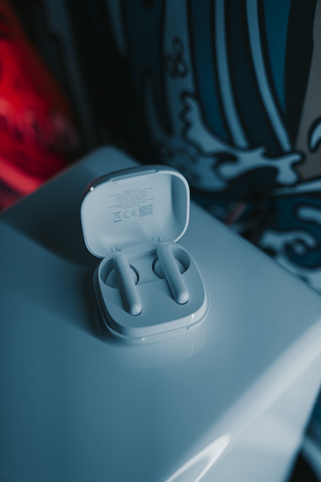 A close-up of a pair of white-colored true wireless earbuds in their charging case on a white surface.