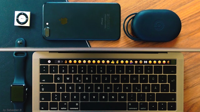 Een grijze iPod, een zwarte iPhone, een zwarte Beats-draagtas, een donkerblauwe Apple Watch en een grijze MacBook.