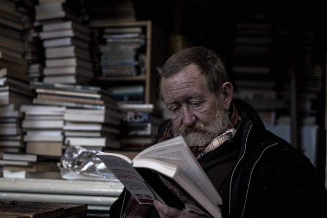 Un homme avec une veste noire lit un livre.