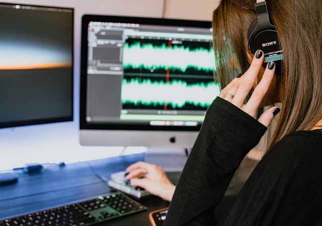 A woman with a black top listens to an audio clip on a pair of Sony headphones.