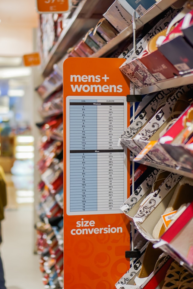 Primer plano de un cartel naranja con una tabla de conversión de tallas de zapatos de hombre y mujer.