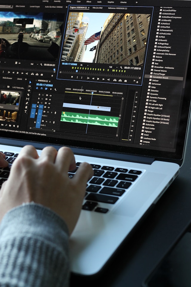 A person uses Adobe Premiere Pro to edit a video on a gray MacBook.