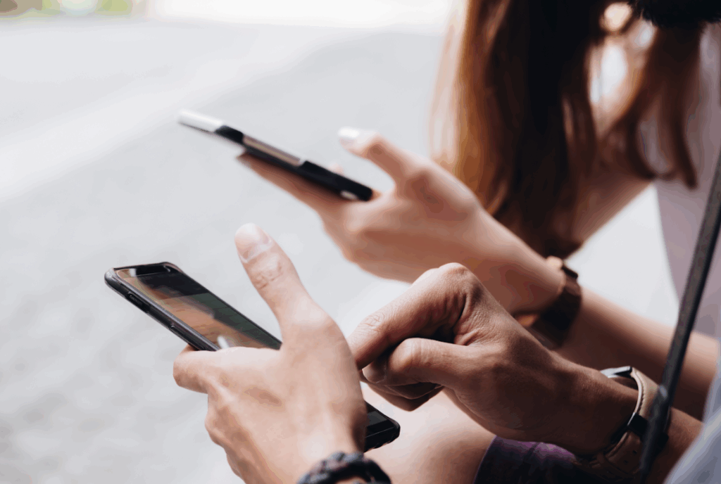 Duas pessoas com os telemóveis na mão no exterior.