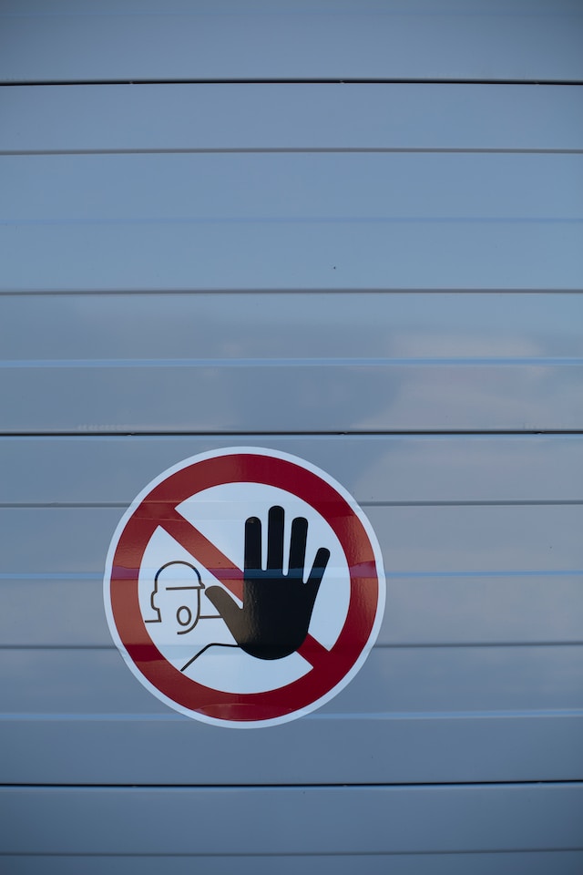 Un perete cu un autocolant cu o persoană care indică oprirea cu palma.