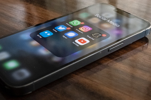 O imagine a unui iPhone negru care afișează un dosar cu aplicații de socializare care conține și aplicația Twitter.