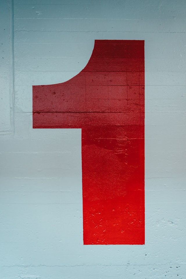 Numărul unu cu vopsea roșie pe un perete alb.
