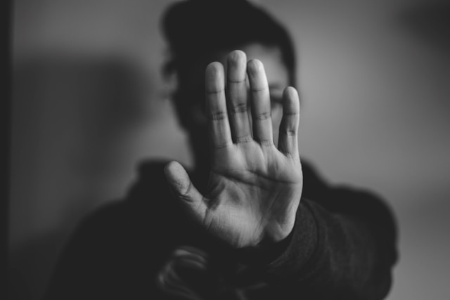 O persoană cu hanorac își întinde mâna și își arată palma.