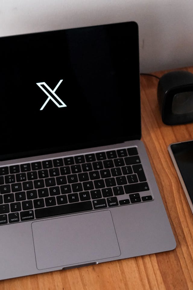 Gri bir Macbook Pro, siyah bir arka plan üzerinde X'i görüntüler.